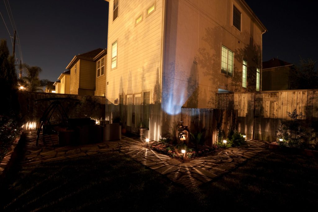 Home exterior lit by uplights and landscape lights at night