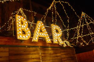 wooden sign, with wooden letters, illuminated with the word "bar"
