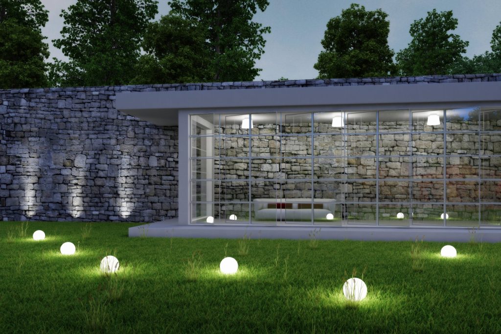 Glowing sphere lights on a lawn beside a stone garden wall