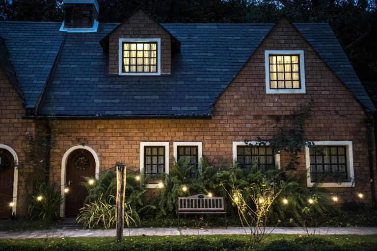 Brick house with lit garden beds in the evening